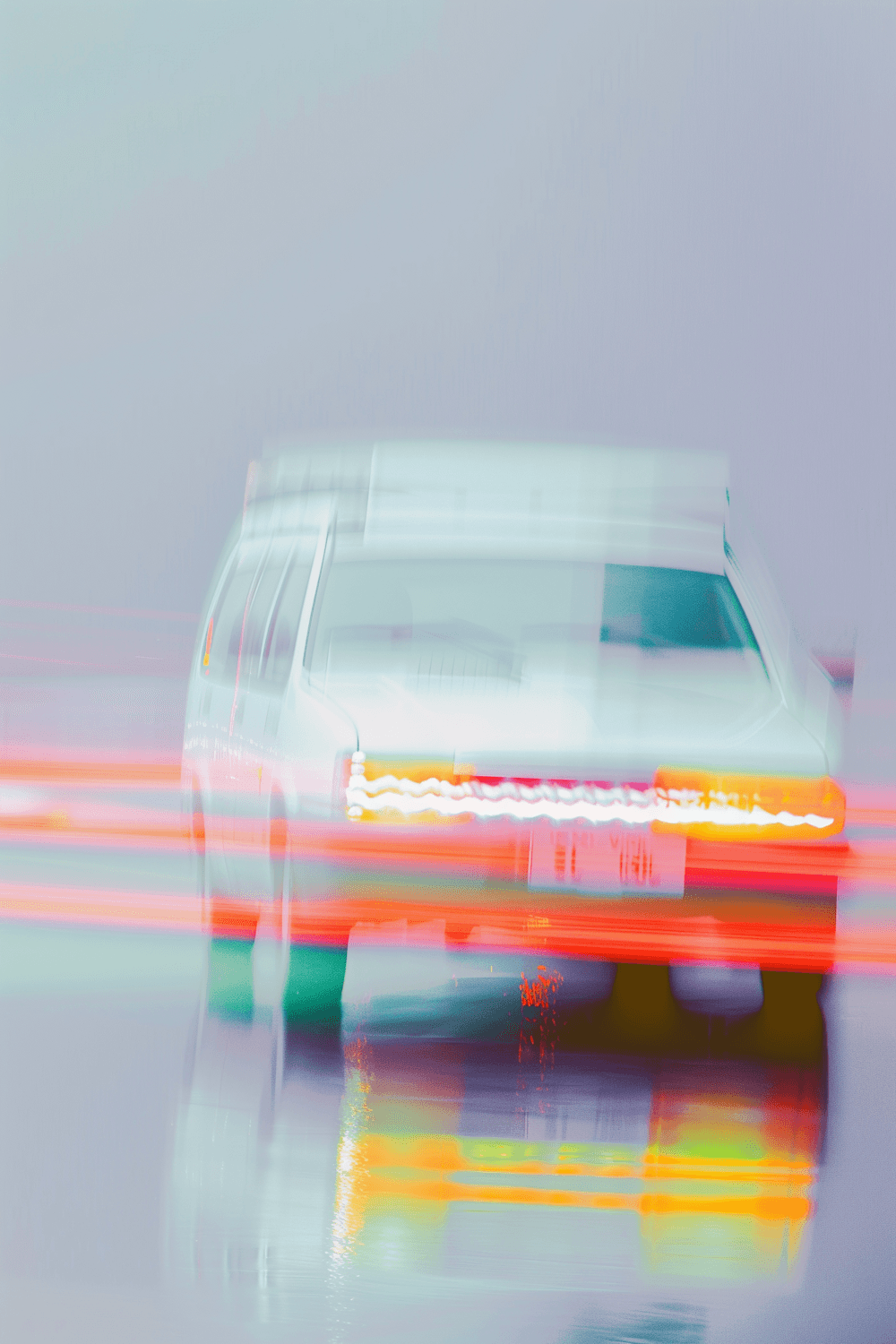 Tail lights streaking across a wet road at speed