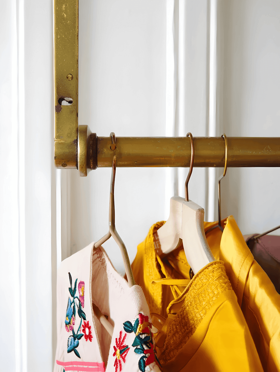Clothing rack holding embroidered garments on wooden hangers