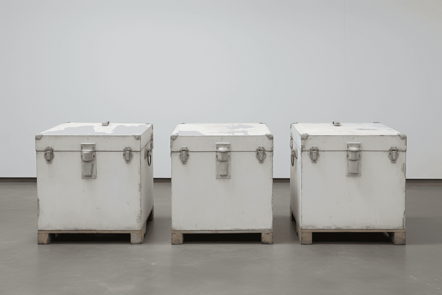 Three white storage crates on wooden pallets